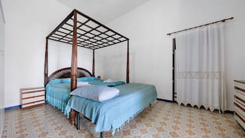 A four-poster bed with a wooden frame, a matching nightstand, and a patterned floor.
