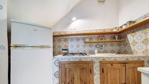 A compact kitchen with a white refrigerator, wooden cabinets, a gas stove, and patterned backsplash tiles.