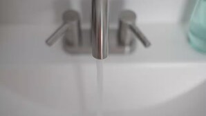 Ein Badezimmer mit einem modernen Wasserhahn und freiem Blick auf den Spülbereich.