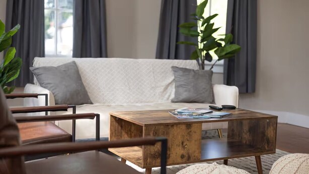 Ein Wohnzimmer mit einer Couch, einem Holztisch und einem Sessel.