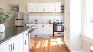 Eine moderne Küche mit weißen Schränken, einem Edelstahlkühlschrank, einem Einbauofen und einem Blumentopf.