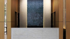 A modern interior with a textured wall, a wooden panel design, and a textured counter. - PAZIRO HOTEL (Dushanbe)