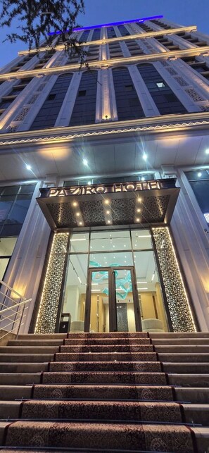 A hotel entrance with a grand staircase leading up to a glass door.