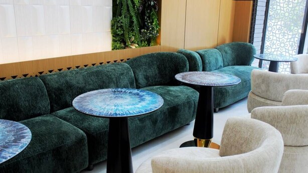 A modern lounge area with a green sofa, round tables, and a white armchair. - PAZIRO HOTEL (Dushanbe)