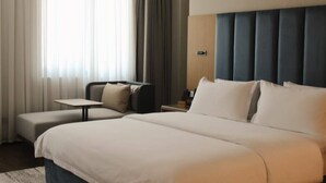 A hotel room with a large bed, a small table, a sofa, and a nightstand. - PAZIRO HOTEL (Dushanbe)