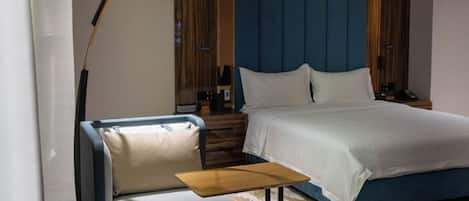 Quarto de hotel moderno com cama, sofá, mesinha e ar condicionado.