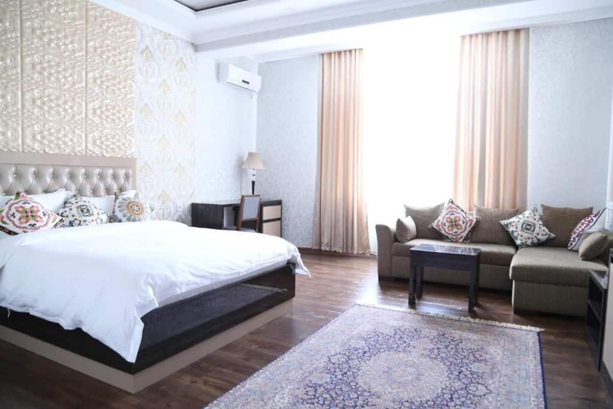Une chambre d’hôtel avec un grand lit, un canapé, une table basse et un tapis à motifs.
