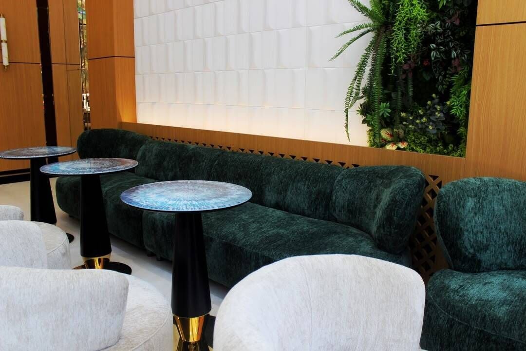 A seating area with a green sofa, round tables, and a vertical garden.