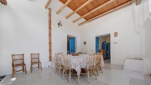 A dining area with a round table, wicker chairs, and a tiled floor.