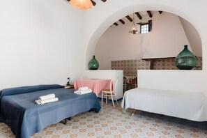 Une chambre avec deux lits, une petite table recouverte d’une nappe rose et des carreaux de sol à motifs.