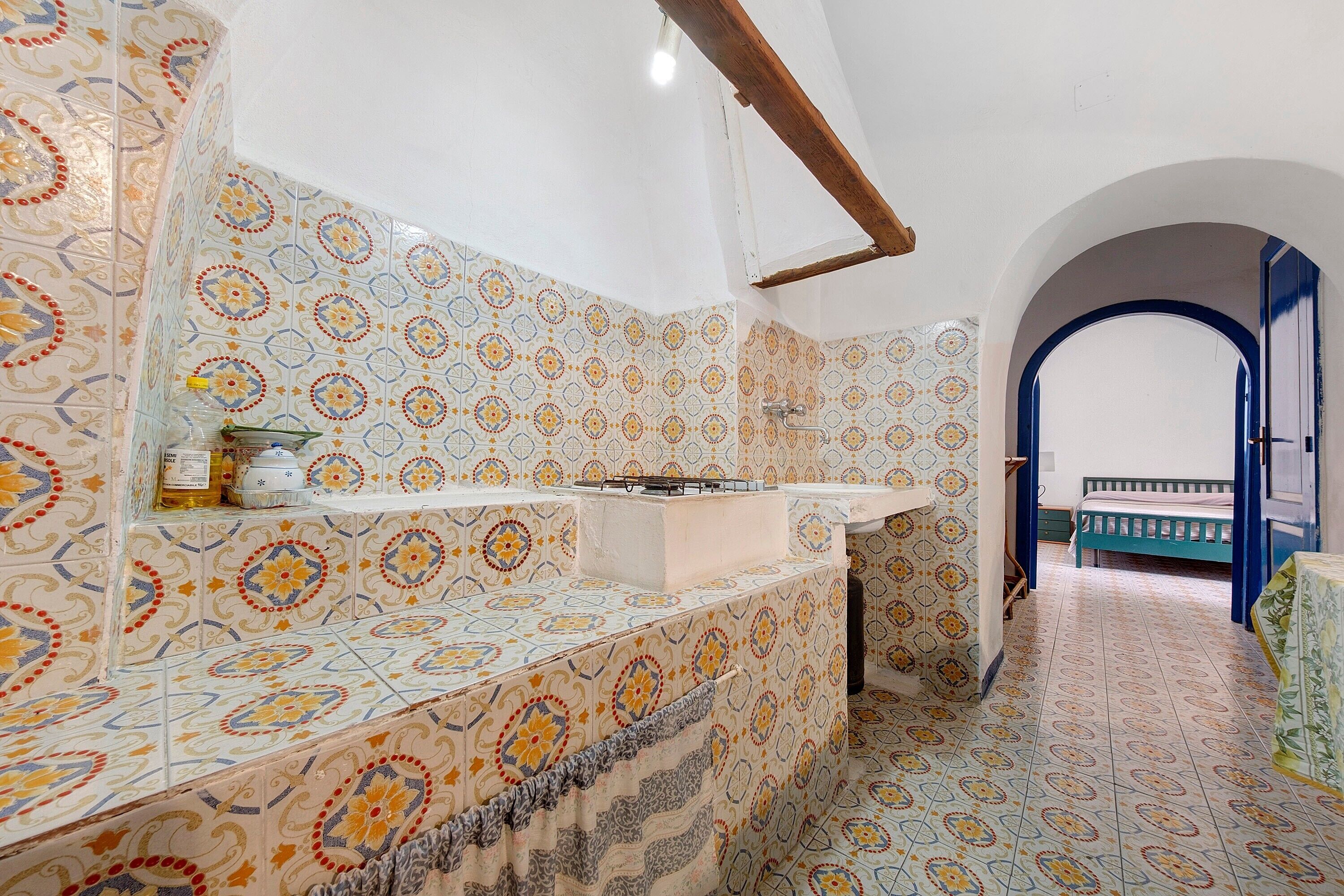 A bathroom with patterned tiles, a sink, and a mirror.