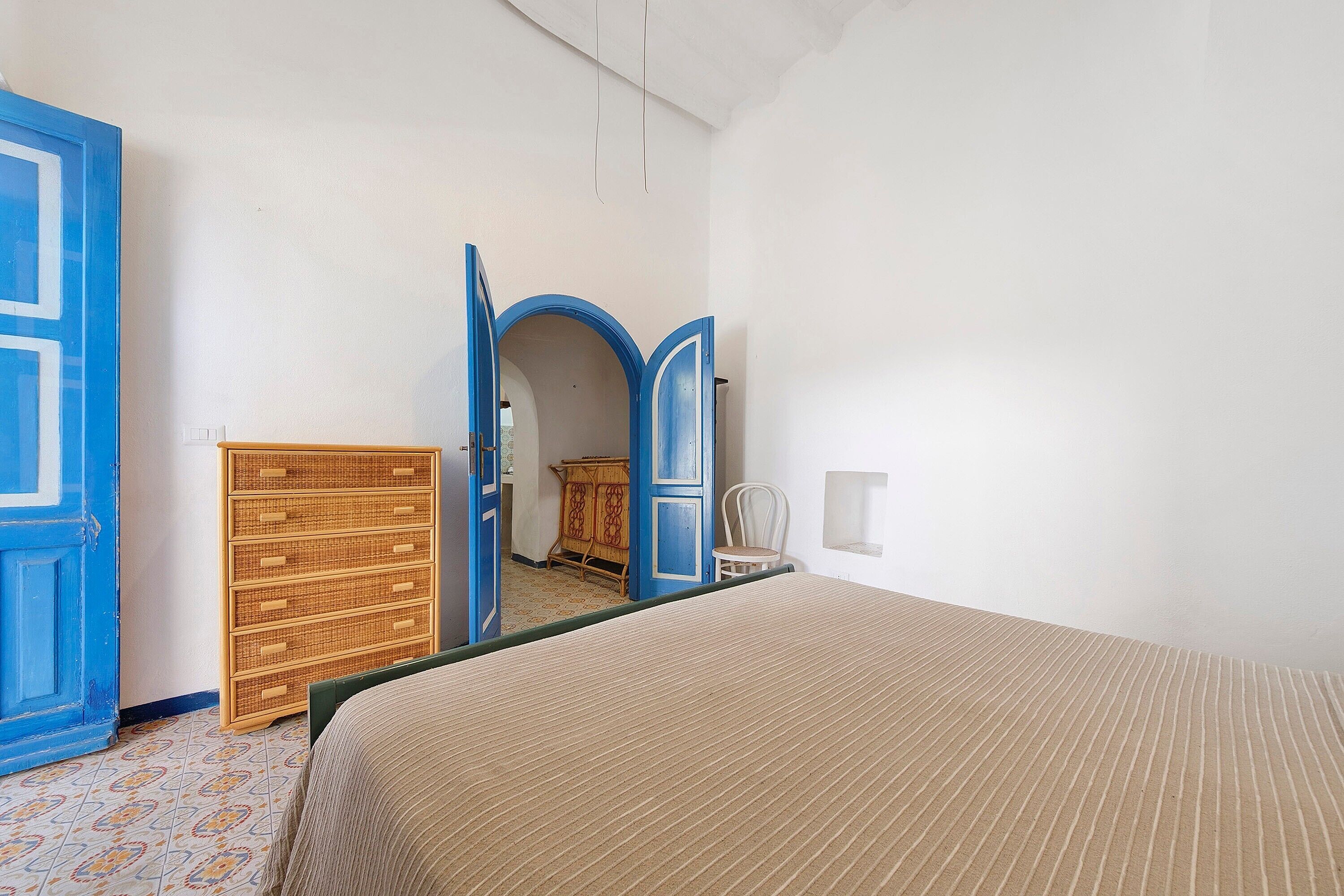 Um quarto com uma cama, cômoda, cadeira e guarda-roupa com espelho.