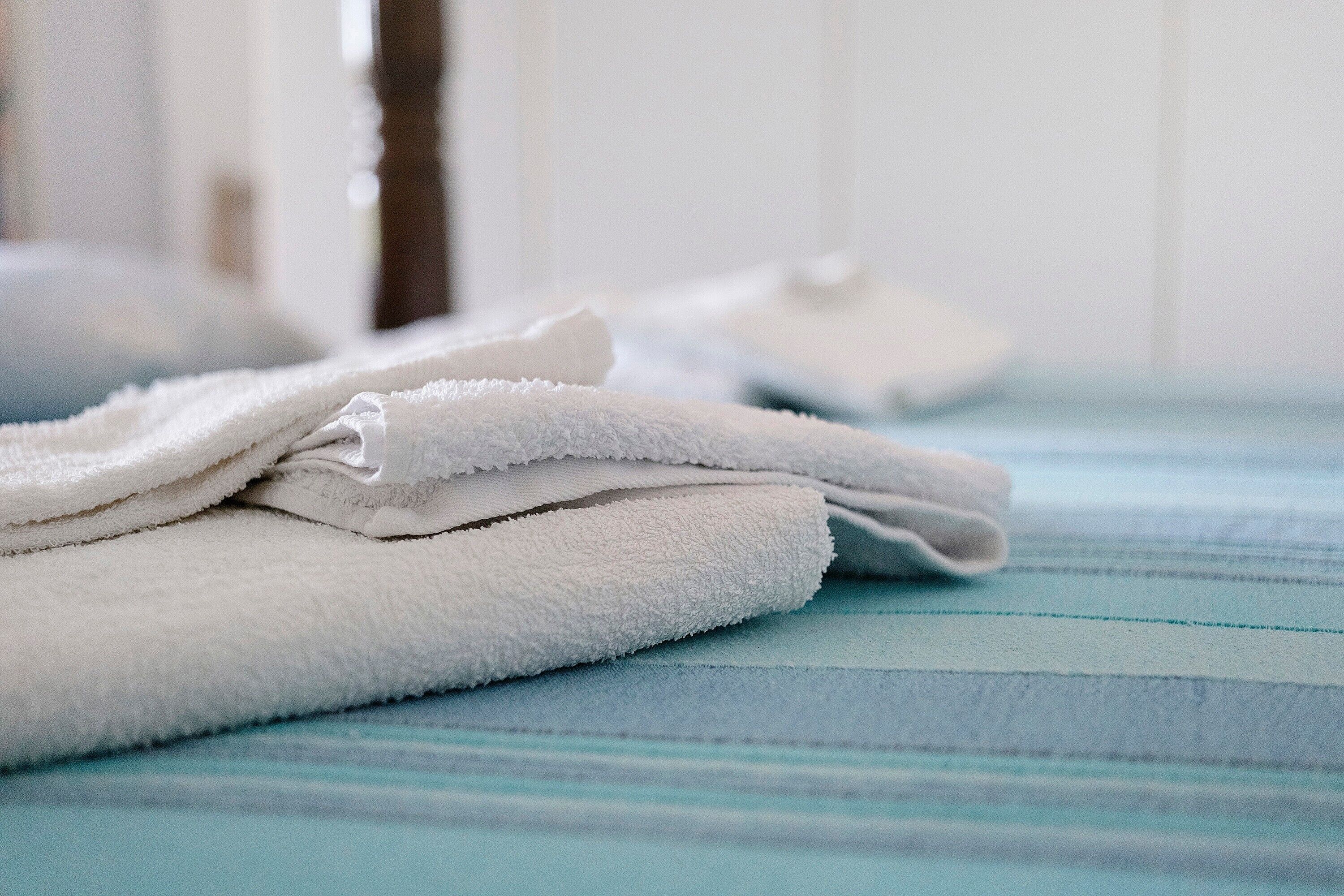A stack of white towels on a bed with a blue striped bedspread.