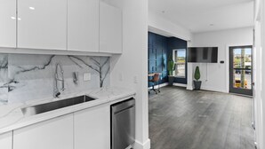 A modern kitchen with white cabinets, a marble backsplash, and a stainless steel sink. - Hyde Park Deluxe private residence (Tampa)