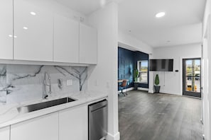 Een moderne keuken met witte kasten, een marmeren achterwand en een roestvrijstalen spoelbak.