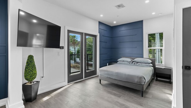 A modern bedroom with a bed, a TV, a potted plant, and a sliding glass door. - Hyde Park Deluxe private residence (Tampa)