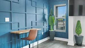 A room with a blue wall, a wooden table, a brown chair, a potted plant, and a TV on the wall. - Hyde Park Deluxe private residence (Tampa)