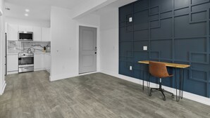 A modern kitchen with white cabinets, a marble backsplash, and a wooden dining table with a brown chair. - Hyde Park Deluxe private residence (Tampa)