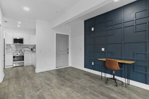 A modern kitchen with white cabinets, a marble backsplash, and a wooden dining table with a brown chair. - Hyde Park Deluxe private residence (Tampa)