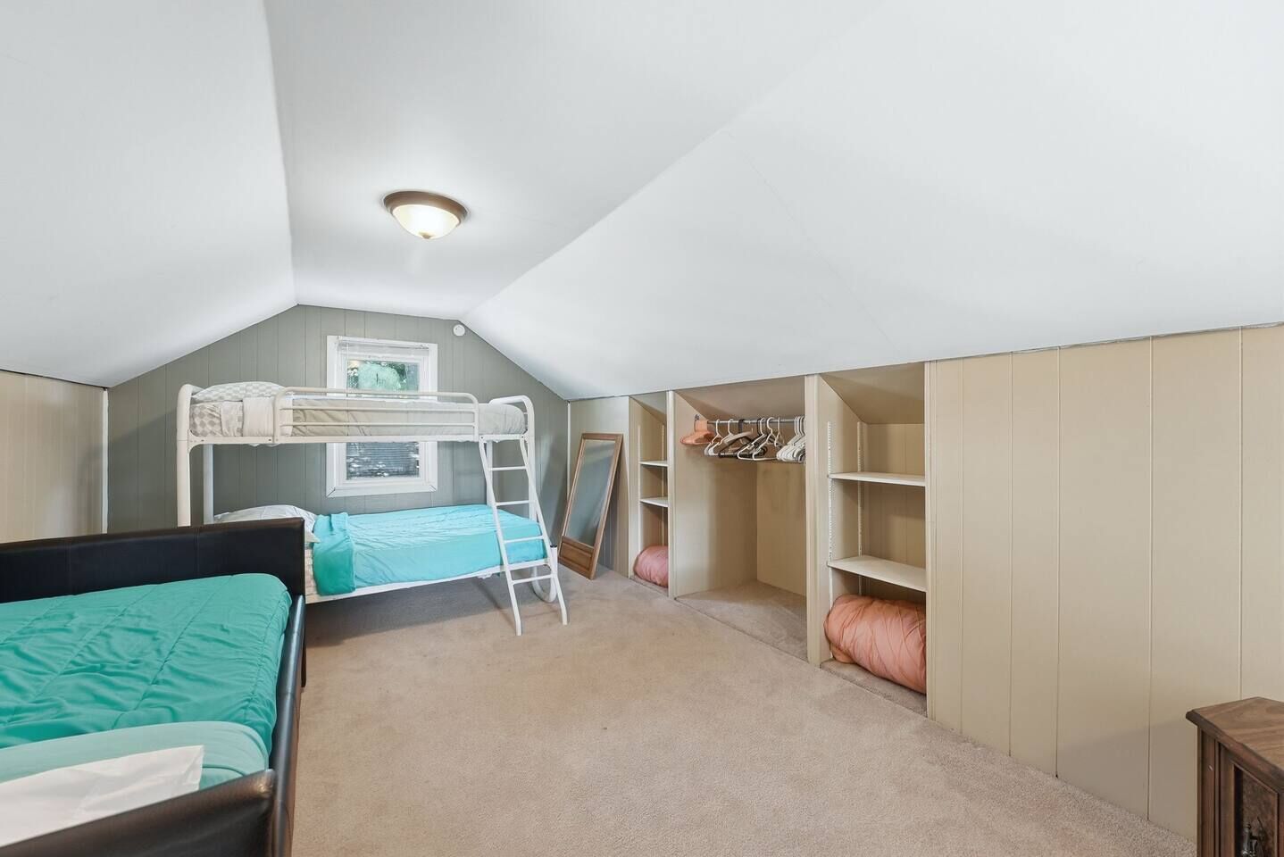 Una habitación con literas, una escalera, un armario y un espejo.
