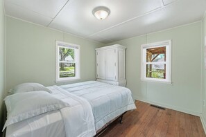 A bedroom with a bed, two windows, a white wardrobe, and a ceiling light. - Lake Haven | Family Getaway with a Pier (North Webster)