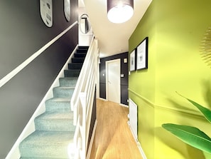 A staircase with a white railing, a green wall, and a door at the bottom.