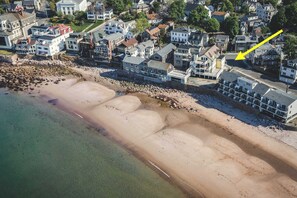 An aerial view of a coastal residential area with houses along the beachfront.