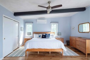 A bedroom with a bed, a ceiling fan, a dresser, and a window.