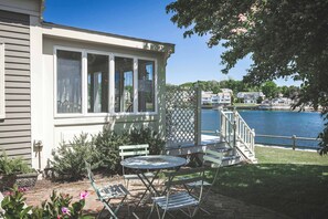 Une terrasse couverte avec une table et des chaises, une terrasse en bois et une vue sur un lac.