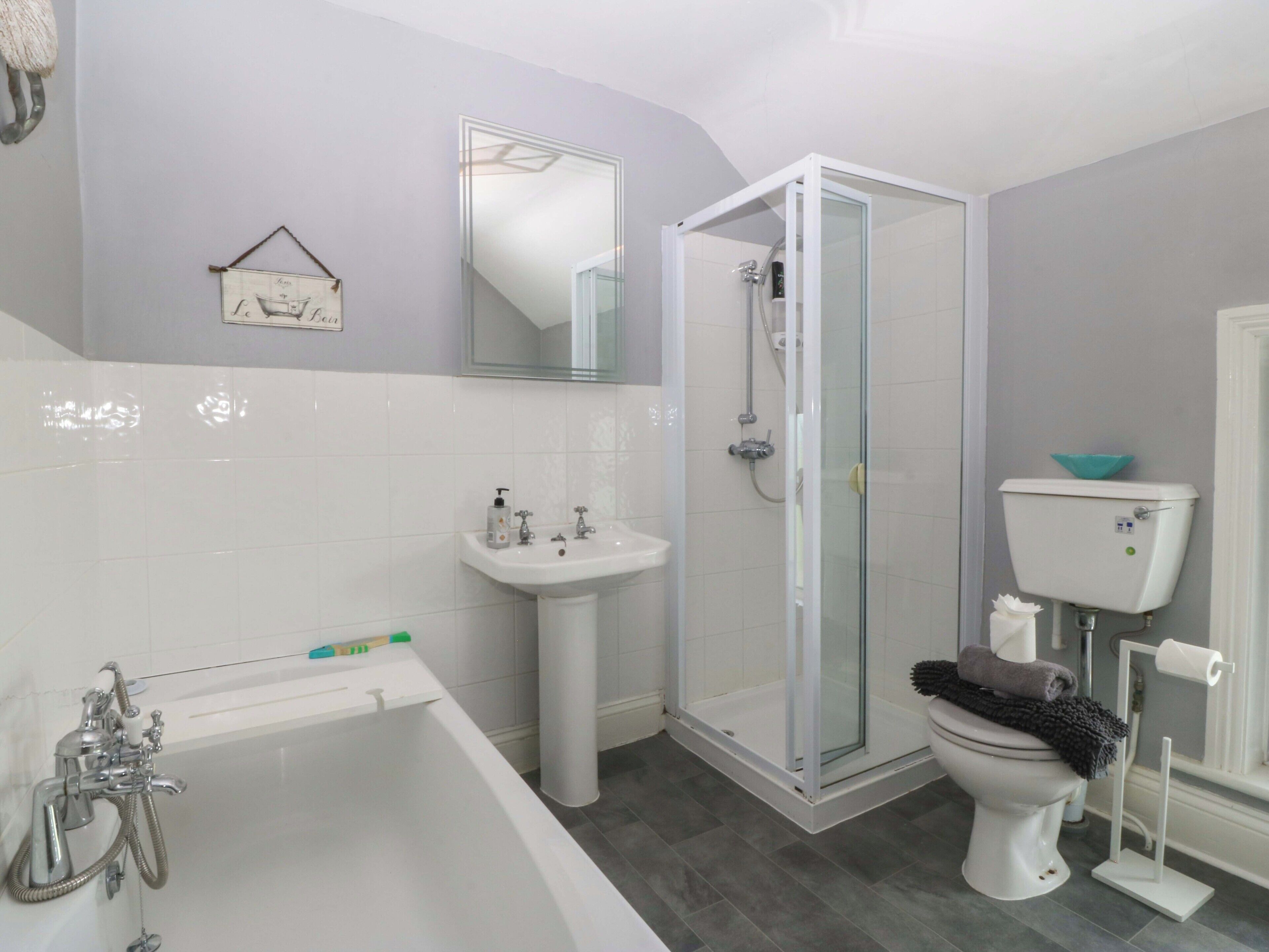 A bathroom with a bathtub, sink, toilet, and a glass-enclosed shower stall.