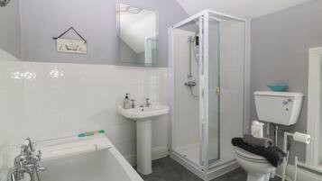 A bathroom with a bathtub, sink, toilet, and a glass-enclosed shower stall.