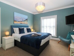 A bedroom with a bed, bedside tables, a desk, a chair, a TV, and a window. - Jack's House (Tywyn)