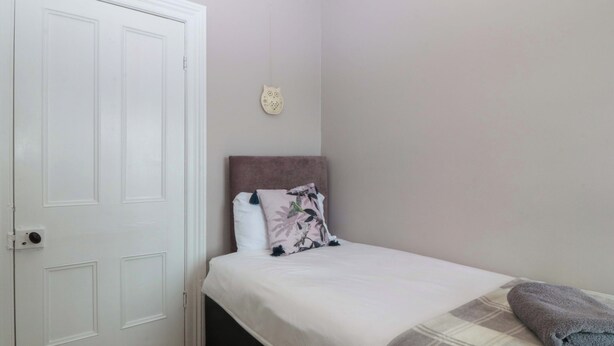 Een slaapkamer met een bed, een witte deur en een decoratie aan de muur.