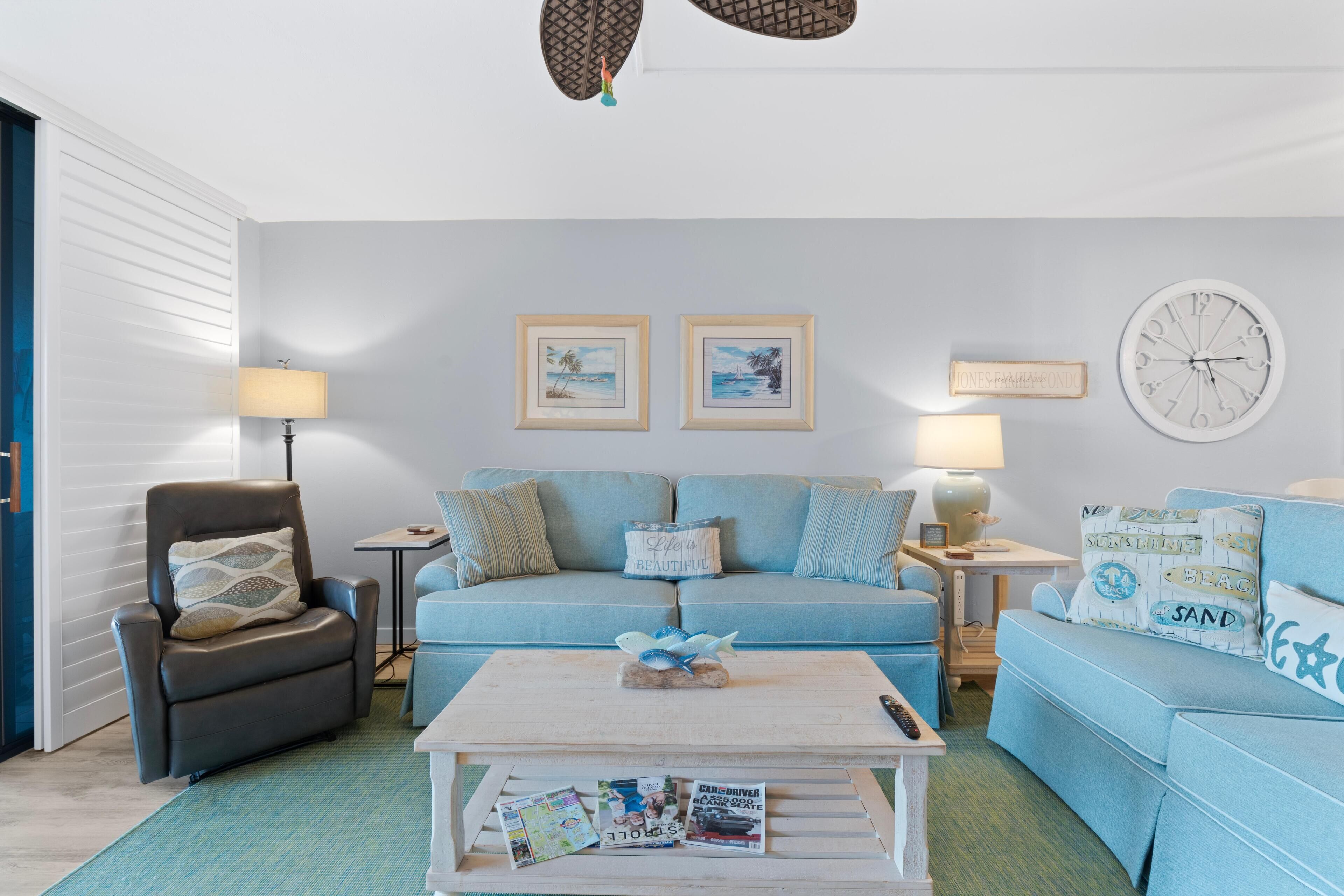 A living room with a sofa, armchair, coffee table, and wall decor.