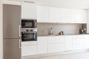 A modern kitchen with white cabinetry, a Bosch oven, and a coffee machine. - Ardantza Bidea - baskeyrentals (Zumaia)