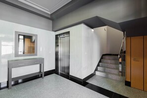 A modern interior with a marble wall, a mirror, a gray console table, a staircase, and an elevator. - Ardantza Bidea - baskeyrentals (Zumaia)
