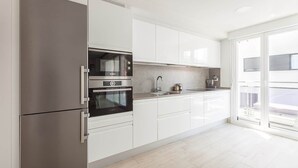 Una cuina moderna amb forn integrat, nevera d'acer inoxidable i una finestra gran.