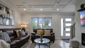 Ein Wohnzimmer mit einem braunen Ledersofa, einem Glastisch und einem gemusterten Teppich.