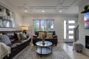 A living room with a brown leather sofa, a glass coffee table, and a patterned rug. - Luxury Toronto Stay with BBQ, Gazebo, Games & Parking (Toronto)