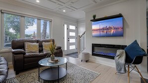 Ein Wohnzimmer mit einer Couch, einem Couchtisch, einem Kamin und einem Fernseher an der Wand.