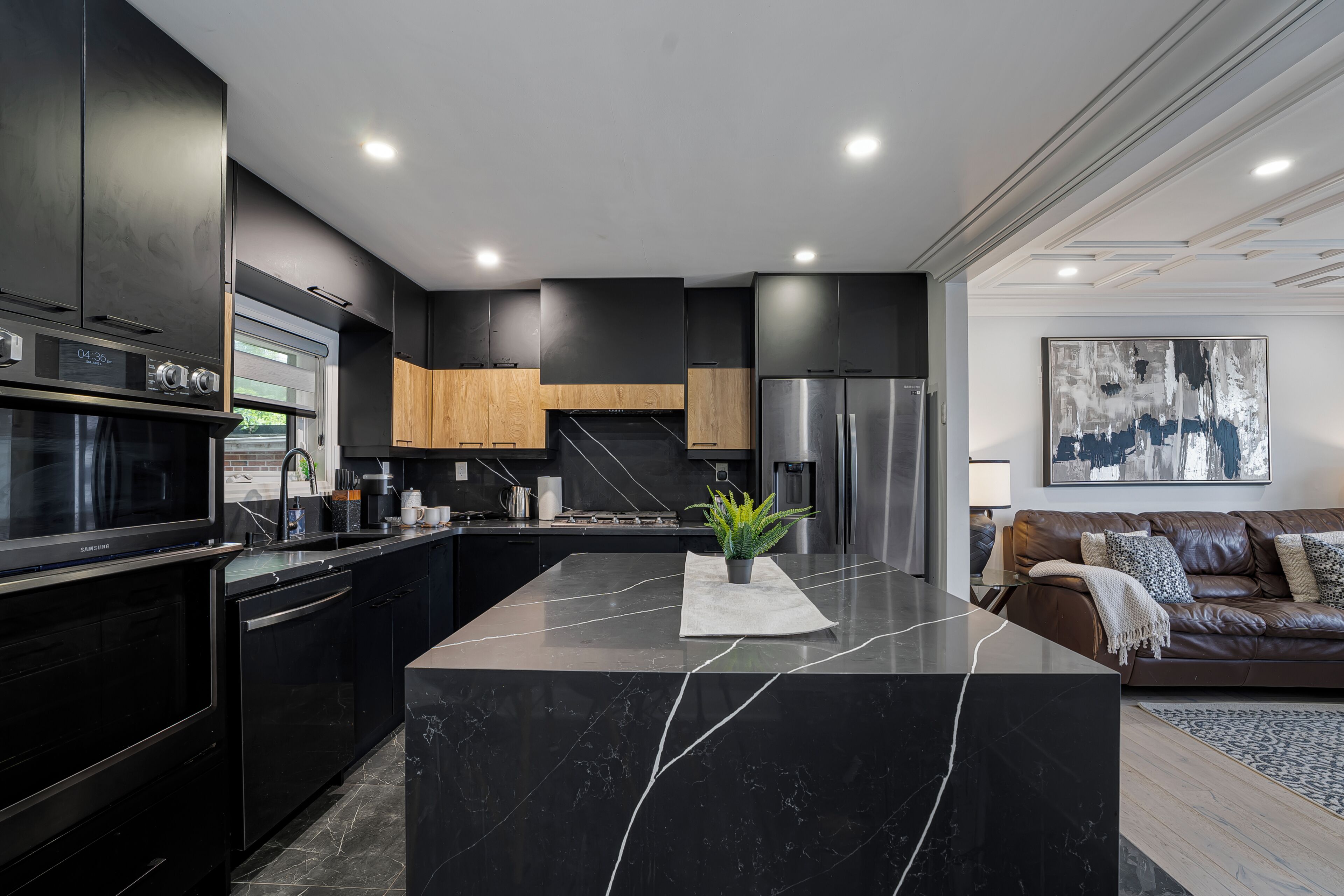 A modern kitchen with a central island, built-in appliances, and a dining area with a brown leather sofa.