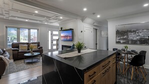 Ein modernes Wohnzimmer mit einer großen Kochinsel, einer Couch und einem Essbereich mit Stühlen und einem Tisch.