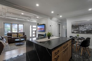 A modern living room with a large island, a sofa, and a dining area with chairs and a table. - Luxury Toronto Stay with BBQ, Gazebo, Games & Parking (Toronto)