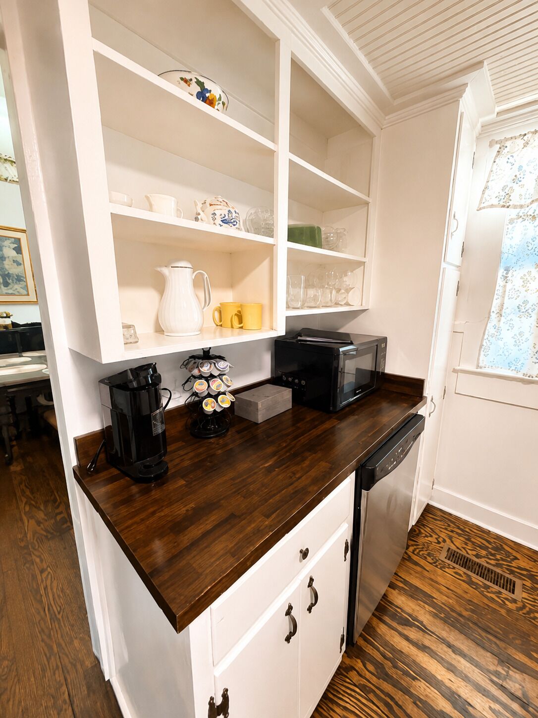 Una cocina con muebles blancos, encimera de madera oscura y lavavajillas.