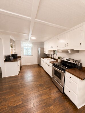 A spacious kitchen with white cabinetry, a stainless steel refrigerator, and a black stove.