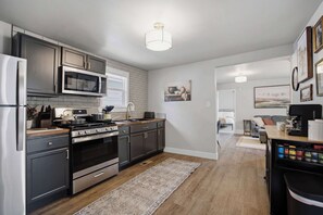 Een moderne keuken met roestvrijstalen apparatuur, donkere kastjes en een houten vloer.