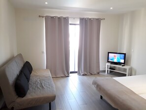 A hotel room with a bed, a sofa, a TV, and a window with curtains. - Dream Studio with Pool in Poente da Aldeia (Albufeira)