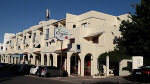 Un immeuble à plusieurs étages abritant un bar-pizzeria au rez-de-chaussée, avec une enseigne comportant un logo et du texte.