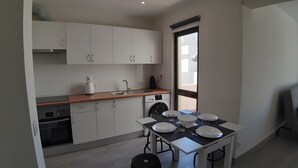 Une cuisine compacte équipée d’un évier, d’une cuisinière et d’un lave-vaisselle, ainsi que d’une table à manger avec de l’assiette, et d’une fenêtre laissant entrer la lumière naturelle.