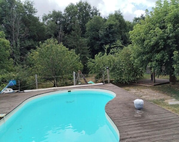 A swimming pool with a wooden deck, surrounded by trees. - Entire house, private pool, and lush garden (1,500 m²) (Espiet)